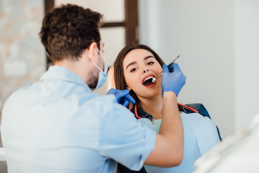 Dentist making professional teeth cleaning withb the cotton, female young patient at the dental office